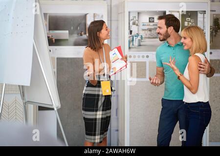 giovane coppia al negozio di arredamento interno che parla con il venditore manager si attestano piastrelle in ceramica cercando di scegliere quelle giuste Foto Stock