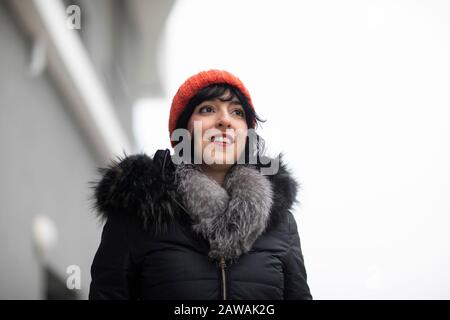 giovane donna con cappuccio rosso in inverno di fronte a edifici moderni Foto Stock