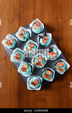 Il piatto di gustose cupcake decorato con fragole, fichi e crema Foto Stock
