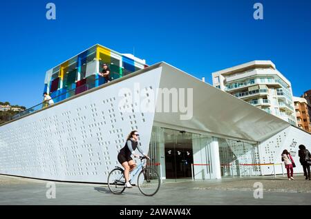 Malaga, Spagna : una giovane donna passa in bicicletta oltre il museo d'arte moderna del Centre Pompidou di Malaga inaugurato nel 2015. Foto Stock