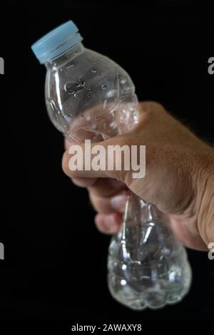 Una bottiglia di plastica vuota schiacciata da una mano mans. Foto Stock