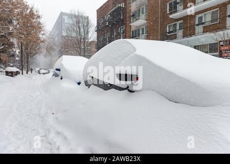 Auto coperte di neve parcheggiate sul lato della strada in un quartiere di Montreal con uomo a piedi in lontananza Foto Stock