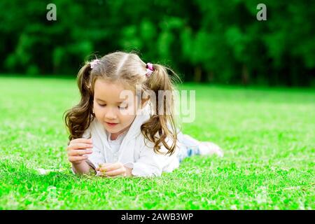 Immagine di un bambino sdraiato sull'erba nel parco Foto Stock