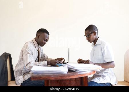 Coppia di uomini neri africani Che Lavorano insieme in un tipico ufficio africano Foto Stock