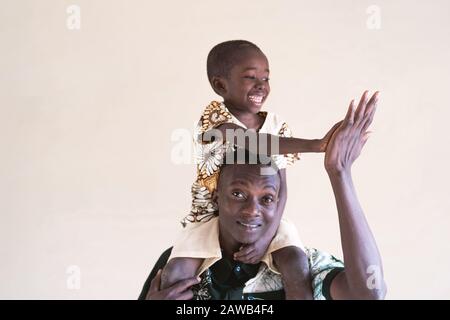 Vera famiglia africana di papà e figlio alto cinque di fronte alla macchina fotografica come una felicità sorridente ridere simbolo Foto Stock