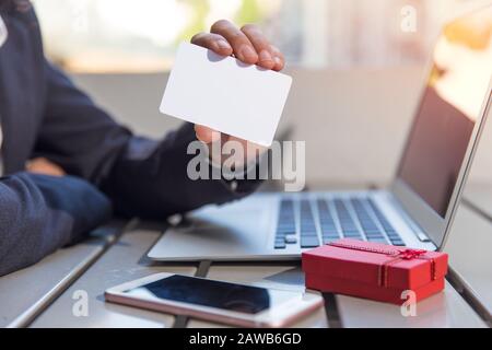 la gente di affari tiene il mockup bianco della carta di credito di plastica con il concetto in linea del regalo di shopping Foto Stock