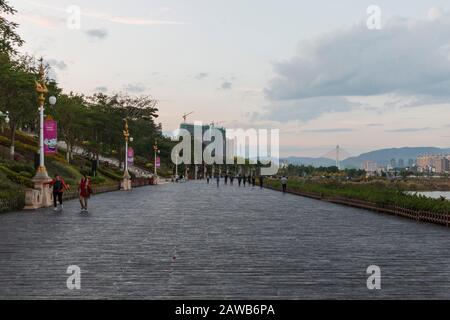 Jinghong, Cina - 2 gennaio 2020: Turisti che camminano lungo il fiume Mekong (Lancang) a Jinghong, capitale Xishuangbanna - Yunnan Foto Stock