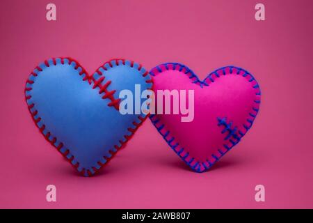 Foglio di gommapiuma cucito a mano blu e rosa cuori giocattolo su uno sfondo rosa per romantico, relazione, San Valentino, Broken Heart Love concetto Foto Stock