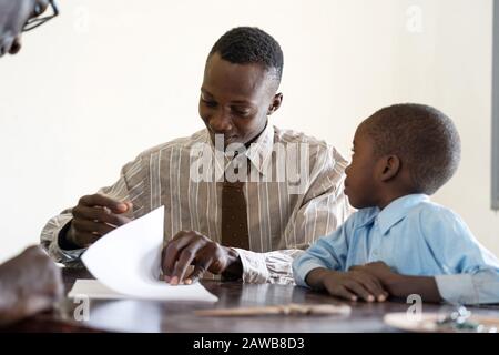 Padre africano e figlio firma documenti per iscrivere il bambino a scuola in Africa a Bamako, Mali Foto Stock