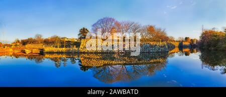 Panoramica riflessione di mura in pietra e storiche torri di avvistamento del castello patrimonio nella città di Himeji del Giappone. Ampia vista panoramica. Foto Stock