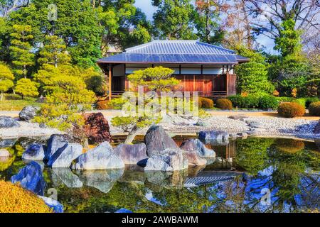 Padiglione in legno nel tradizionale giardino giapponese con laghetto e pini in una giornata di sole nel parco Nijo di Kyoto. Foto Stock