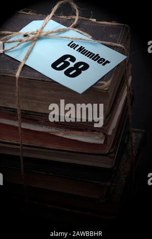 Antichi libri impilati in un mucchio legato con stringa con numero di casa d'asta lotto su una etichetta blu tag. Concetto di asta di antiquariato Foto Stock