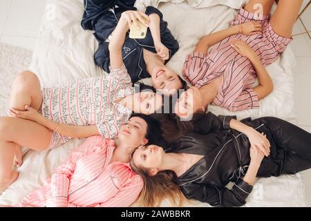 Ragazze graziose in pigiami che prendono selfie sul letto. Foto Stock