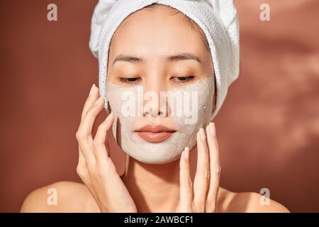 Giovane bella donna con argilla maschera facciale. Trattamento Spa, self care e pelle sana Foto Stock