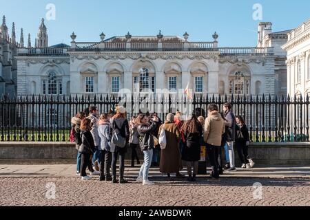 Un gruppo di tour a piedi che si trova all'esterno delle scuole OID, della Camera del Senato e della Chiesa di Great St Mary, Cambridge, Regno Unito Foto Stock