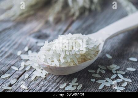 Riso bianco con un cucchiaio di legno su una stele. Riso Jasmine per cucinare. Primo piano. Foto Stock