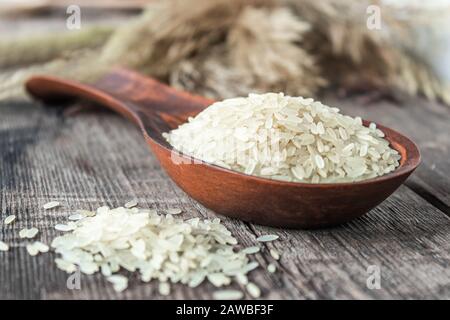 Riso bianco con un cucchiaio di legno su una stele. Riso Jasmine per cucinare. Primo piano. Foto Stock
