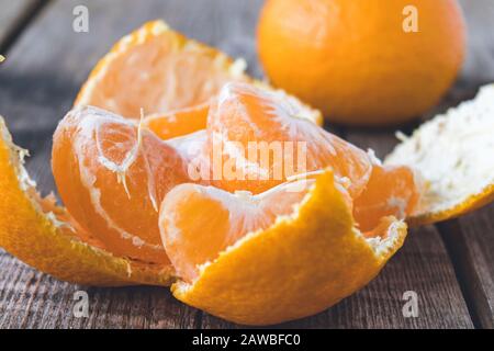Mandarino sbucciato senza buccia e fette di mandarino maturo sono sul tavolo. Agrumi tangerini o arance. Primo piano. Foto Stock