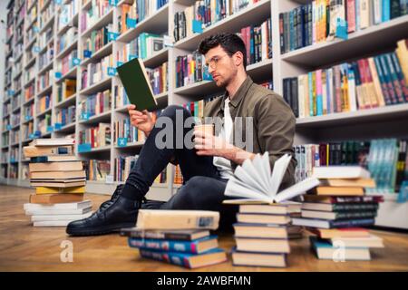 Ragazzo legge un libro in una biblioteca. Concetto di curiosità, immaginazione e cultura Foto Stock