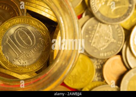 Monete di paesi diversi in un vaso di vetro. Molte monete metalliche di diverse denominazioni e di vari paesi. Contesto finanziario. Rublo russo Foto Stock