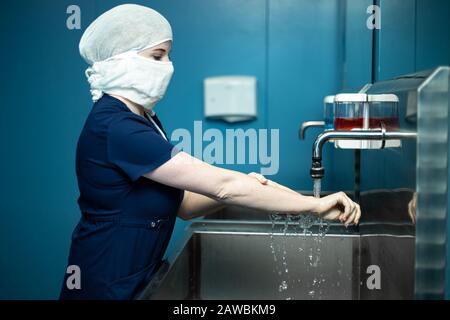 Il medico chirurgo nella maschera medica disinfetta le mani prima dell'intervento chirurgico. Foto Stock