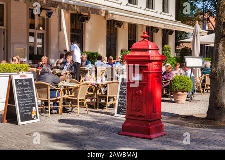 25 settembre 2018: Bruges, Belgio - I Clienti che si trovano all'esterno di una sala da tè e di una cassetta postale rossa, nel cuore storico della città vecchia. Foto Stock