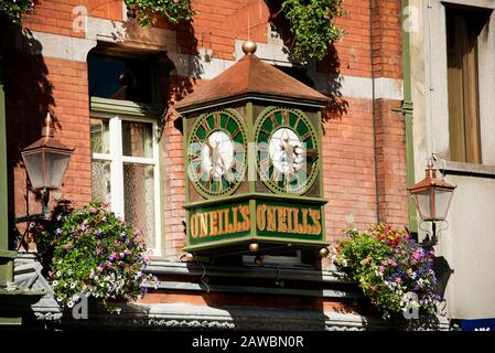 Centro Di Dublino. Orologio Presso O'Neills Bar Suffolk Street Dublin. Orologio da parete in stile vittoriano con vecchie lampade da parete e cestini di fiori Foto Stock
