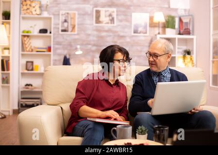 Nonna e nonno usando un computer portatile per chattare con i loro nipoti. Le persone anziane usando tecnologie moderne Foto Stock