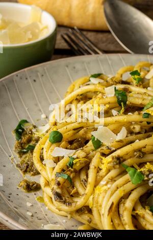 Pasta con pesto e parmigiano rasato su superficie in legno. Primo piano. Foto Stock