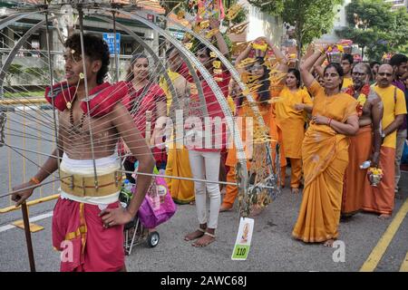 Per il festival indù di Thaipusam, un partecipante etnico cinese sta portando un palo attaccato con pentole di latte; India Piccola, Singapore Foto Stock