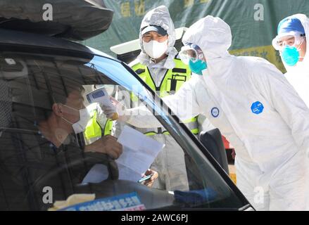 Wenzhou, Cina. 08th Feb, 2020. Maurizian Hosany Sumayyah misura la temperatura corporea per un autista in un nuovo checkpoint di prevenzione e controllo del coronavirus di un'uscita autostradale a Wenzhou, nella provincia di Zhejiang della Cina orientale, 8 febbraio 2020. Pakistan Abdul Zahir Hamad e Mauriziano Hosany Sumayyah, una coppia sposata, entrambi lavorano come medici al PanHealth Medical Center di Wenzhou. Dallo scoppio del nuovo coronavirus, essi sono stati al servizio di volontari in un checkpoint di uscita autostradale a Wenzhou, controllando le informazioni di identità e misurando la temperatura corporea per i conducenti e i passeggeri. ' Credito: Xinhua Foto Stock