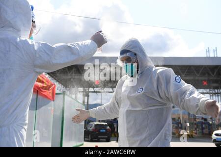 Wenzhou, Cina. 08th Feb, 2020. Il pakistano Abdul Zahir Hamad (R) è disinfettato in un nuovo checkpoint di prevenzione e controllo del coronavirus di un'uscita autostradale a Wenzhou, nella provincia di Zhejiang della Cina orientale, 8 febbraio 2020. Pakistan Abdul Zahir Hamad e Mauriziano Hosany Sumayyah, una coppia sposata, entrambi lavorano come medici al PanHealth Medical Center di Wenzhou. Dallo scoppio del nuovo coronavirus, essi sono stati al servizio di volontari in un checkpoint di uscita autostradale a Wenzhou, controllando le informazioni di identità e misurando la temperatura corporea per i conducenti e i passeggeri. "Dobbiamo fare credito a qualcuno: Xinhua Foto Stock