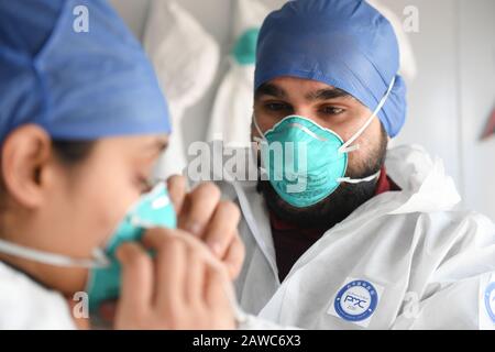 Wenzhou, Cina. 08th Feb, 2020. Pakistan Abdul Zahir Hamad (R) aiuta sua moglie Mauriziano Hosany Sumayyah indossare la maschera prima di entrare in lavoro in un nuovo coronavirus prevenzione e controllo checkpoint di un'uscita autostradale a Wenzhou, Cina orientale Zhejiang Province, 8 febbraio 2020. Pakistan Abdul Zahir Hamad e Mauriziano Hosany Sumayyah, una coppia sposata, entrambi lavorano come medici al PanHealth Medical Center di Wenzhou. Dallo scoppio del romanzo coronavirus, sono stati al servizio come volontari in un checkpoint di uscita autostradale a Wenzhou, controllo delle informazioni di identità e misurazione del credito: Xinhu Foto Stock