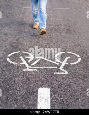 Uomo che cammina su una pista di bicicletta separata per andare in bicicletta infrangendo le regole. Andare su un percorso sbagliato Foto Stock