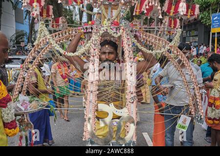 Per il festival indù di Thaipusam, un partecipante sta portando un elaborato Kavadi, compreso un simbolo sacro OM (ॐ), in onore di dio Murugan; Singapore Foto Stock
