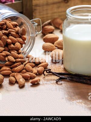 Latte di mandorla non latte sostitutivo su un tavolo di legno. Frutta a guscio e vetro con latte, latte senza lattosio sostituto per vegani Foto Stock