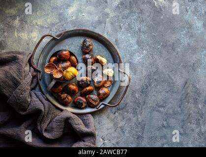 castagne al forno, fritte su sfondo grigio scuro, pronto a mangiare, copia spazio Foto Stock