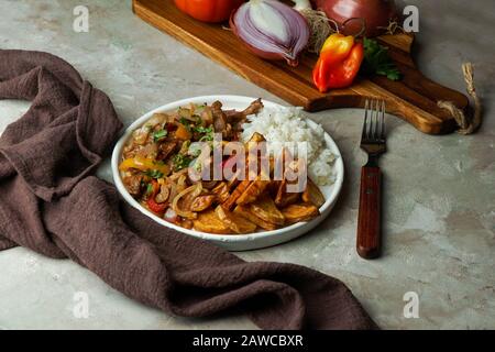 Piatto peruviano lomo saltado, composto da filetto di manzo con cipolla rossa, peperoncino giallo, pomodori, patate fritte e riso. Copia spazio Foto Stock