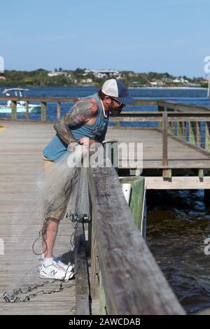 Un pescatore tatuato si prepara a gettare la sua rete nella tasca del Manatee al Sandsprit Park di Port Salerno, Florida, USA. Foto Stock
