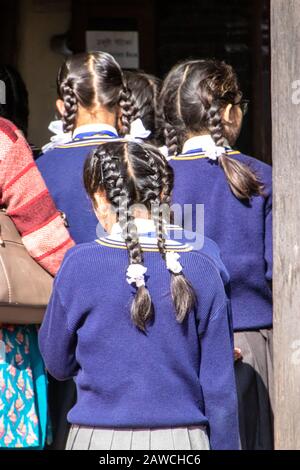 Bhaktapur Durbar Square, Khwopa, Kathmandu, Nepal, Asia - 9 dicembre 2019: Ragazze scolastiche con uniforme scolastica e trecce quando entrano in un edificio, hanno girato Foto Stock