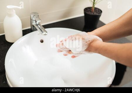 Uomo che lava le mani con sapone sotto acqua corrente Foto Stock