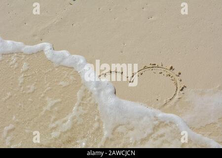 Il cuore scrisse nella sabbia e si lavò via dalle onde. Foto Stock