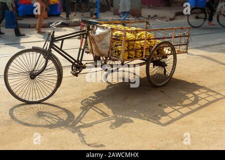 Corsa in risciò cargo con banane sulla strada. Calcutta. India Foto Stock