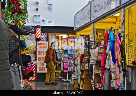 Mercato interno "nuovo" di Carmarthen. Gli acquirenti che esplorano bancarelle colorate. Articoli mulit-colorati per la vendita Foto Stock