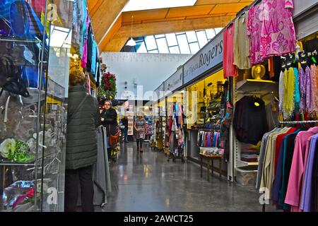 Mercato interno "nuovo" di Carmarthen. Gli acquirenti che esplorano bancarelle colorate. Articoli mulit-colorati per la vendita Foto Stock