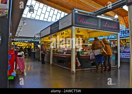 Mercato interno "nuovo" di Carmarthen. Gli acquirenti che esplorano bancarelle colorate. Foto Stock