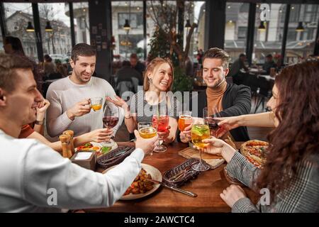 Felice multirazziale giovani amici rilassarsi insieme parlando ridere sedersi al tavolo da caffè, allegro diversi studenti ragazze e ragazzi gente gruppo di studio Foto Stock