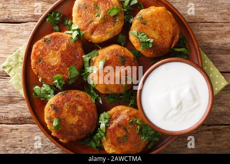 Gustoso Aloo Tikki è un popolare cibo di strada indiano che è fondamentalmente croccante e piccante patate patty con yogurt primo piano in un piatto sul tavolo. Orizzontale Foto Stock