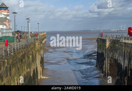 L'ingresso al Porto di Portishead e al Porto di Marina Quays al largo del canale di Bristol in una soleggiata giornata di febbraio. Vecchie mura del porto e ingresso fangoso con bassa marea Foto Stock