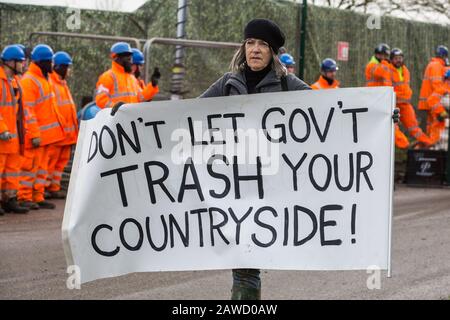 Harefield, Regno Unito. 8 Febbraio 2020. Una donna porta un banner anti-HS2 durante l'azione da parte di attivisti ambientali di Save the Colne Valley, Stop HS2 e Extinction Rebellion per impedire la costruzione di opere di abbattimento degli alberi per il progetto ferroviario ad alta velocità. Gli attivisti hanno avuto successo nel prevenire uno qualsiasi degli alberi di linea che felling da HS2 e dopo un intervento da parte di un poliziotto tutti gli alberi di abbattimento e il lavoro traboccante è stato ora annullato per il fine settimana. Credit: Mark Kerrison/Alamy Live News Foto Stock